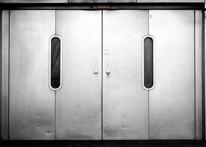 A freight elevator with heavy sliding doors on level zero, the ground floor.